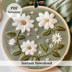 an embroidery pattern with white flowers and green leaves