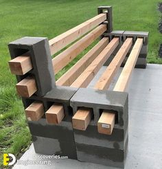 a park bench made out of concrete blocks on the side of a sidewalk with grass in the background