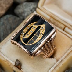 This fantastic antique initial ring features a a rectangular cut black onyx tab. The onyx is accented with the calligraphy letter "O" made with inlay high carat gold and diamond accents. The onyx has very small nicking at the edges. The ring is crafted in 10k yellow gold that has a rosy color to it. The gold has been left unpolished and with its rich natural patina. The inside of the ring is engraved "Emilcito." Luxury Men's Yellow Gold Onyx Ring, Antique Signet Ring With Diamond Accents For Formal, Antique Signet Ring With Diamond Accents For Formal Occasions, Antique Black Enamel Signet Ring, Luxury Diamond Signet Ring Collectible, Luxury Rectangular Onyx Jewelry, Elegant Signet Ring As Collectible, Luxury Rectangular Initials Jewelry, Antique Black Enamel Signet Ring As Gift