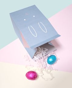 a blue paper bag sitting on top of a table next to two colorful eggs and candy