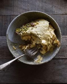 a bowl filled with food on top of a wooden table next to a knife and fork