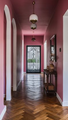 a hallway with pink walls and wood floors