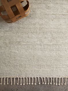 an area rug with fringes on the floor and a wooden chair next to it