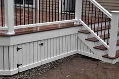 a wooden deck with white railing and handrails on the side of a house