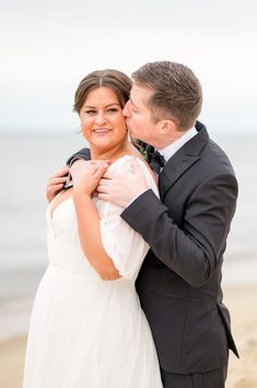 a bride and groom kissing on the beach