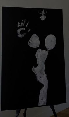 a black and white photo with hand prints on the wall next to an easel