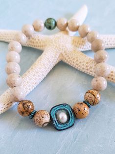 Get those sandy vibes flowing with our Beachy Bracelets, featuring natural stones, patina green accents, pearls, and cute ocean-inspired charms. Our Mykonos Collection would not be complete without some versatile, easy-to-use stretch bracelets. Wear one alone or stack a few for a bold BoHo look. Each bracelet features antiqued patina charms and spacers made in Greece, where the art of metal finishing was popular already thousands of years ago. Pearls, stingrays, shells, and other fun shapes ador Beachy Bracelets, Bold Boho, Patina Green, Vacay Vibes, African Turquoise, Ocean Inspired, Stretchy Bracelets, Picture Jasper, Green Accents