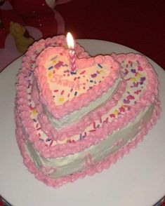 two heart shaped birthday cakes sitting on top of a white plate with a lit candle