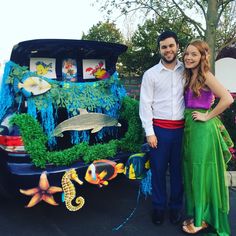 a man and woman standing in front of a car decorated with sea life on it