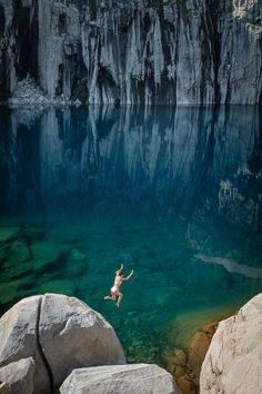 a person jumping into the water from rocks