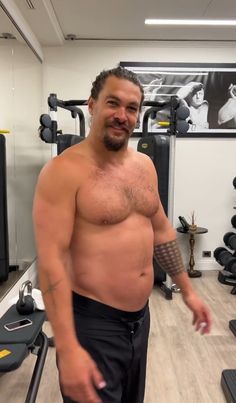 a man without a shirt standing in a gym