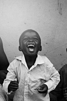 a young boy laughing while standing next to other people