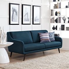 a blue couch sitting on top of a white rug in a living room next to two framed pictures