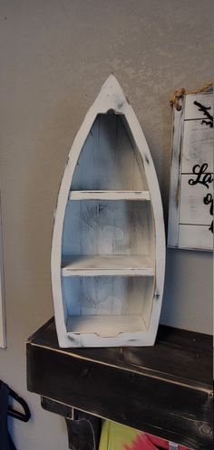 a boat shaped shelf sitting on top of a wooden table next to a white wall