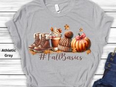 Get ready for the cozy season with our #FallBasics t-shirt This adorable design features all the fall essentials--cozy boots, a warm knit hat, a pumpkin spice latte, and a cute pumpkin, all surrounded by autumn leaves. Perfect for lovers of everything fall, this t-shirt is made from a soft, high-quality cotton blend that will keep you warm and stylish during those crisp autumn days. Whether you're going on a pumpkin patch trip, enjoying a fall festival, or simply sipping on your favorite seasona Trendy Comfortable Fit T-shirt For Fall, Trendy Comfort Fit T-shirt For Fall, Casual Everyday Winter T-shirt, Cozy Graphic Print T-shirt For Fall, Trendy Winter T-shirt For Everyday, Fall Basics, Pumpkin Spice Shirt, Seasonal Drinks, Cozy Boots