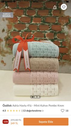 towels stacked on top of each other in front of a brick wall with an orange ribbon