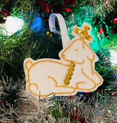 a white ornament hanging from a christmas tree decorated with gold sequins