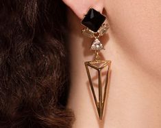 "Add a dose of style to your outfits with these striking art deco earrings. Made of brass with a luxurious 18k gold plating, they ensure a luxurious feel without the hefty price tag. These 1920s earrings come with a bold design, featuring a black stone and a minimalist triangle. The tasteful rhinestones and crystals enhance the design and add a subtle sparkle, forming the perfect combination that will turn heads. With the stylish geometric design, this bold pair will bring the wow effect to any Art Deco Metal Earrings For Evening, Clip-on Art Deco Earrings For Evening, Gold Art Deco Earrings For Party, Black Art Deco Earrings For Evening, Dangle Art, 1920s Earrings, Gold Statement Jewelry, Black Crystal Earrings, Art Deco Jewelry Vintage