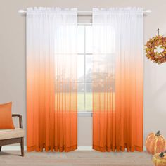 an orange and white ombreed curtain hangs in front of a window with pumpkins