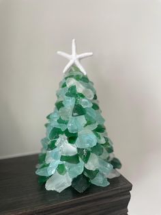 a small christmas tree made out of green glass pieces with a starfish on top