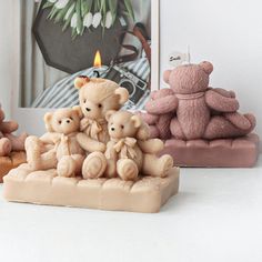 three small teddy bears sitting next to each other in front of a photo and candle