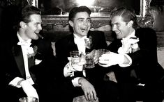 three men in tuxedos are toasting each other