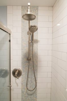 a shower head and hand held shower faucet in a white tiled bath room