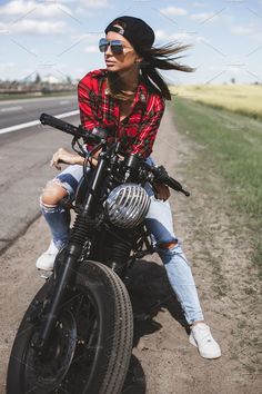 a woman sitting on top of a motorcycle in the middle of an empty road - stock photo - images