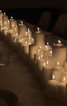 many lit candles are lined up on the table