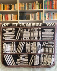 a crocheted book bag sitting on top of a couch in front of bookshelves