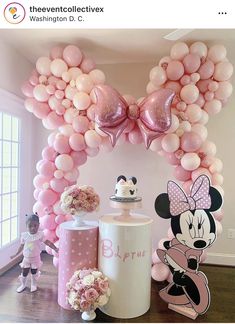 a minnie mouse balloon arch is decorated with balloons and other decorations for a birthday party