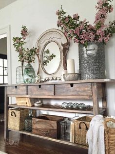 a shelf with baskets and flowers on top of it in front of a wall mirror