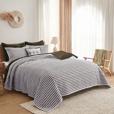 a bed in a bedroom with white walls and wooden flooring next to a window