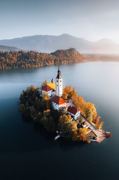 an island in the middle of water with a church on it, surrounded by trees