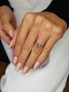 a woman's hand with a diamond ring on her finger and pink manicures