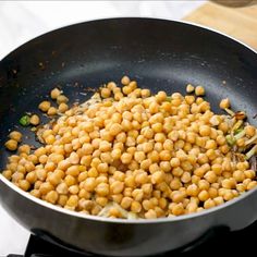 chickpeas are being cooked in a wok on top of the stovetop