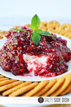 a white plate topped with cheese and cranberry sauce next to some crackers