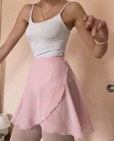 a woman wearing a pink skirt and white tank top is posing for the camera with her hands out