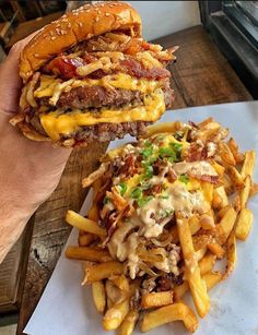 a person holding up a cheeseburger and french fries