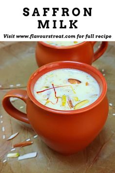 two red mugs filled with soup sitting on top of a table