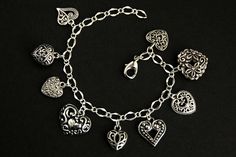 A collection of silver filigree-style heart charms have been dispersed around a shimmering silver plated bracelet chain in this handmade charm bracelet. This heart charm bracelet is then completed with a lobster clasp and a 1/2 inch of chain at the end for adjustable sizing. Charms in this bracelet include nine assorted heart charms in various decorative filigree designs. ● Sizing ● To determine your bracelet size, do a snug measurement of your wrist's circumference, then add 1/2 an inch. 6 to 6 Silver Heart-shaped Nickel-free Bracelet, Silver Nickel Free Heart Bracelet, Elegant Silver Charm Bracelet With Heart Beads, Silver Double Heart Metal Bracelet, Silver Metal Double Heart Bracelet, Heart-shaped Bracelets With Dangling Charms, Silver Charm Bracelet With Heart Beads, Silver Heart-shaped Bracelets With Charms, Silver Heart Bracelet With Charms