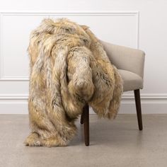 a chair with a fur blanket on it in front of a white wall and floor