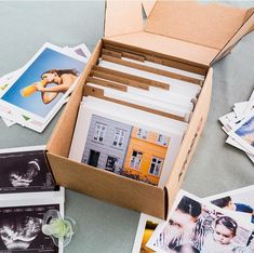 an open box filled with pictures next to postcards and glasses on top of a table