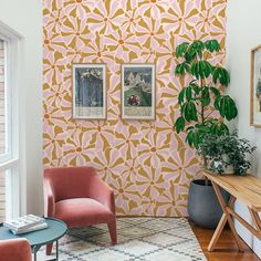 a living room with two chairs and a table in front of a wallpapered wall