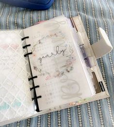 an open notebook with writing on it sitting on top of a blue and white blanket