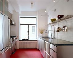 a kitchen with red flooring and stainless steel appliances