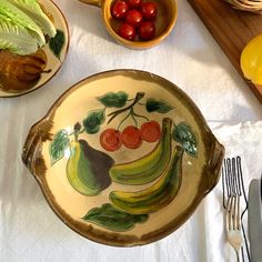 a table topped with plates and bowls filled with fruit on top of a white table cloth