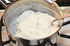 a metal bowl filled with cream sitting on top of a stove