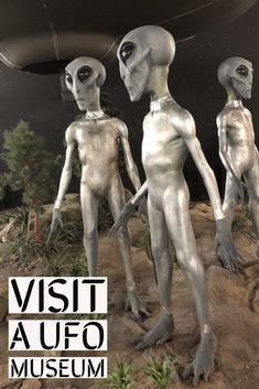 three alien statues are standing in front of a museum sign with the words visitaufo on it