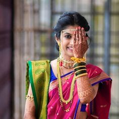 a woman in a colorful sari holding her hands up to her face and smiling